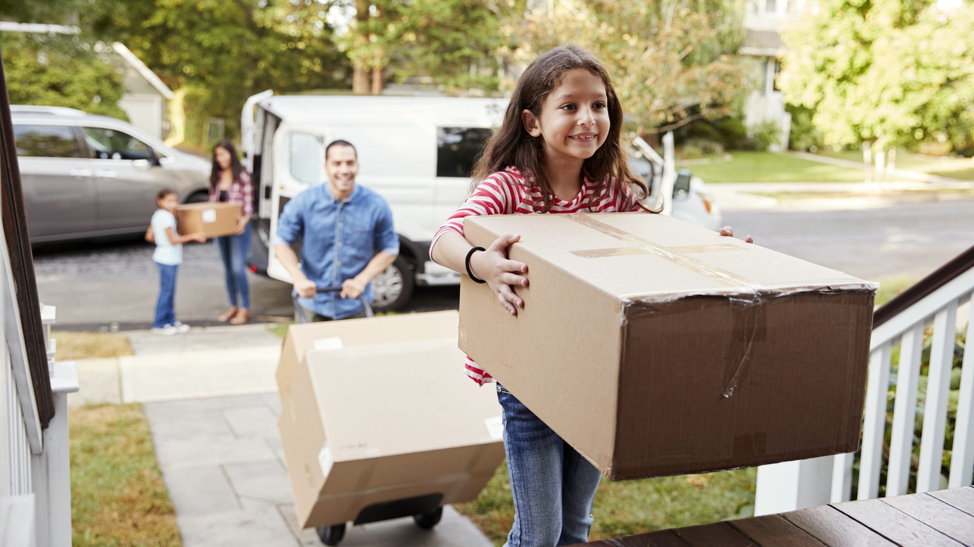 Children Helping Unload Boxes From Van On Family Moving In Day