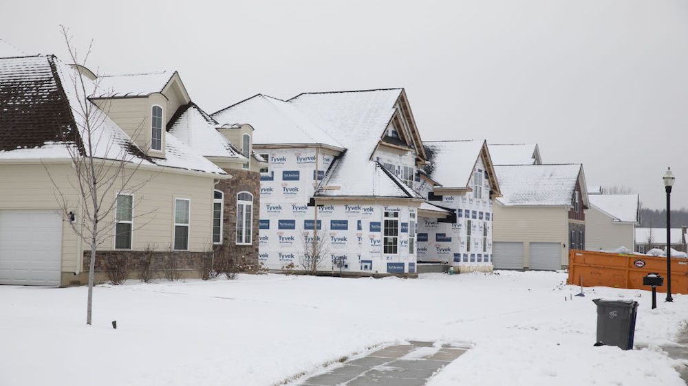 A new home under construction stands between completed houses